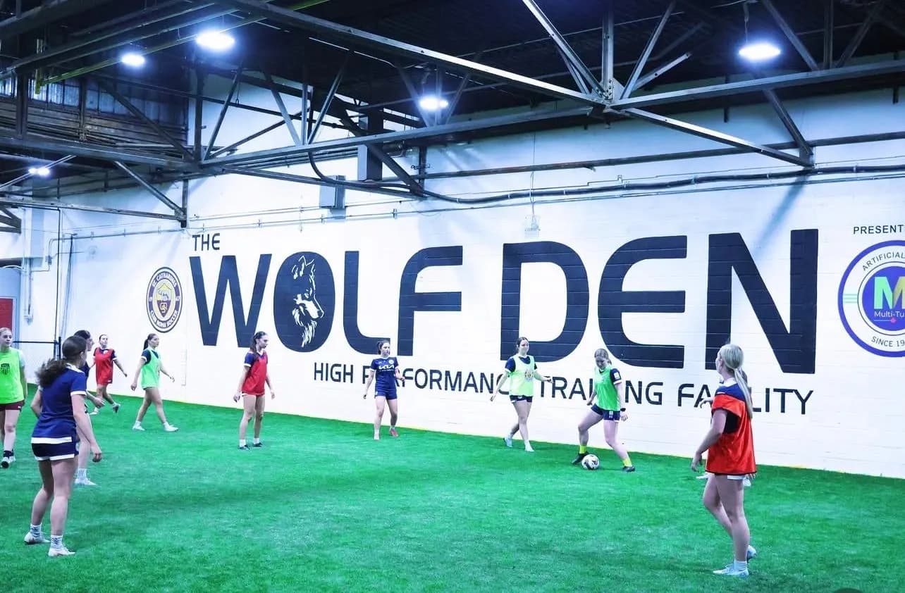 Players training on the indoor turf beneath the Wolf Den wall mural